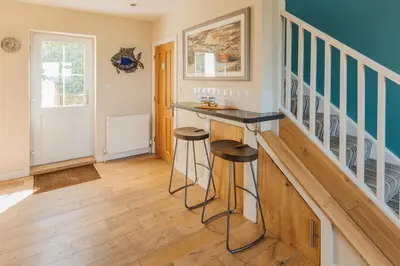 a home bar with stools in a room with stairs at Sunset Sands in St Merryn