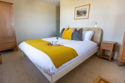 a bedroom with a large bed with a yellow blanket at Sunset Sands in St Merryn