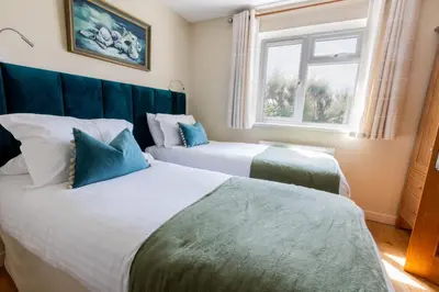 two beds in a room with a window at Sunset Sands in St Merryn