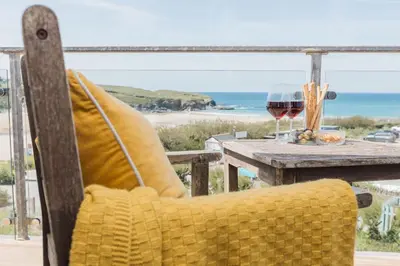 a chair sitting at a table with a glass of wine at Sunset Sands in St Merryn