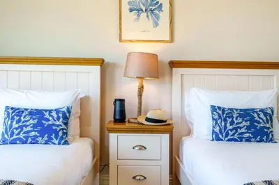 two beds with blue and white pillows and a lamp at Tranquil Shores in Carbis Bay