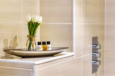 a vase of white flowers on a shelf in a bathroom at Tranquil Shores in Carbis Bay