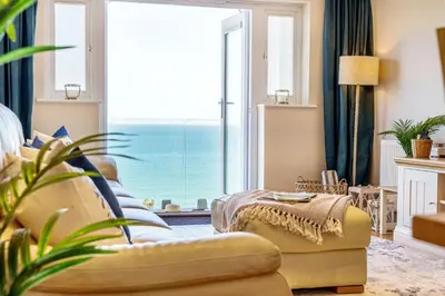a living room with a couch and a large window at Tranquil Shores in Carbis Bay