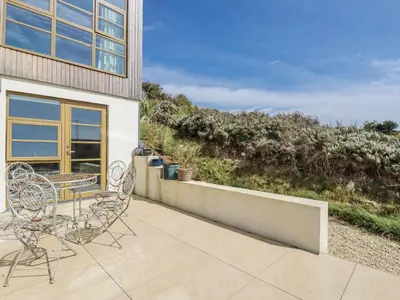 a patio with two chairs and a table on a balcony at Teach Tra West in Perranporth