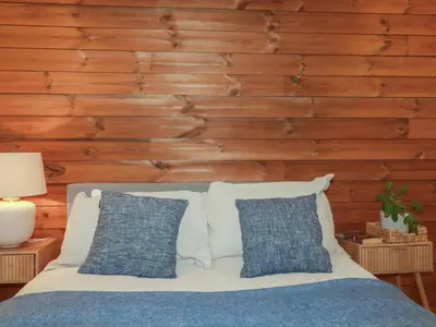 a bed with blue and white pillows and a wooden wall at Teach Tra West in Perranporth