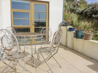 two chairs and a table on a patio at Teach Tra West in Perranporth