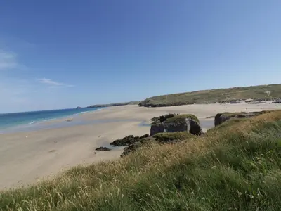 a sandy beach with rocks and the ocean at Teach Tra West in Perranporth