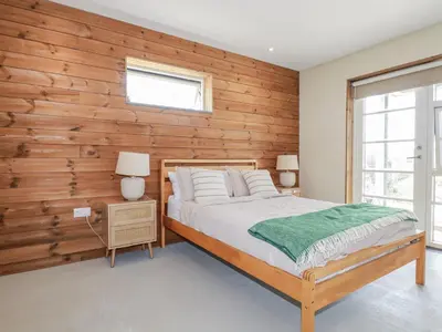 a bedroom with a wooden accent wall and a bed at Teach Tra East in Perranporth