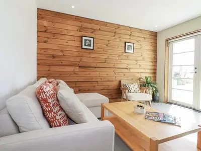 a living room with a couch and a wooden wall at Teach Tra East in Perranporth