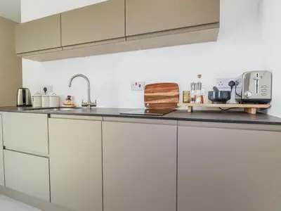 a kitchen with white cabinets and a sink at Teach Tra East in Perranporth
