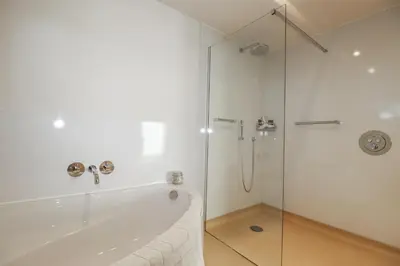 a white bathroom with a tub and a shower at Hilbre in Padstow