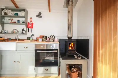 a kitchen with a stove with a fire in it at Hilbre Shepherd Hut in Padstow