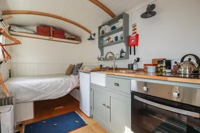a small kitchen with a bed and a sink in a room at Hilbre Shepherd Hut in Padstow