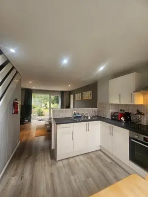 a kitchen with white cabinets and black counter tops at Newquay Coast and Cabin in Saint Columb Road Station