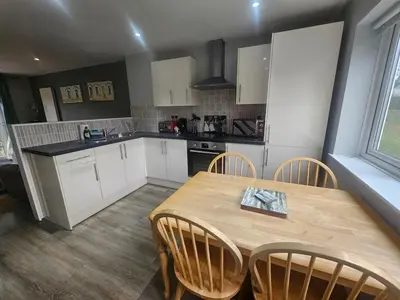 a kitchen with a wooden table and chairs in a kitchen at Newquay Coast and Cabin in Saint Columb Road Station