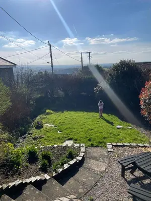a person standing in a yard with a sprinkler at Klys cottage in Saint Breward