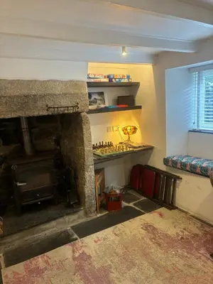 a living room with a stone fireplace and a couch at Klys cottage in Saint Breward