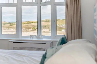 a bedroom with a bed and a table and windows at 5 Bed in Newquay oc-c33035 in Newquay