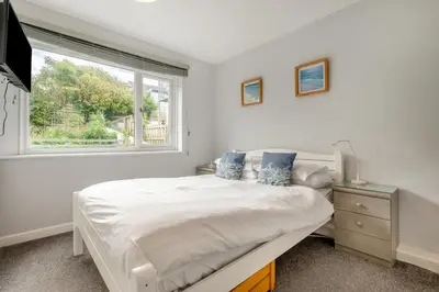 a white bedroom with a bed and a window at 5 Bed in Newquay oc-c33035 in Newquay