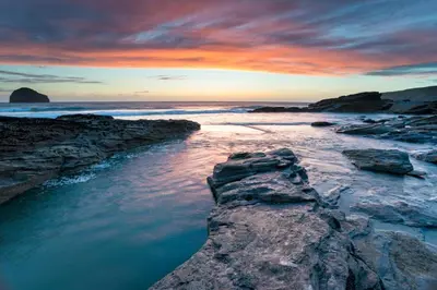 a sunset over the ocean with rocks in the water at 5 Bed in Newquay oc-c33035 in Newquay