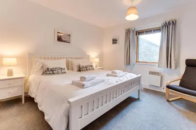 a bedroom with a white bed with a chair and a window at 2 Bed in Porthleven oc-p00890 in Porthleven