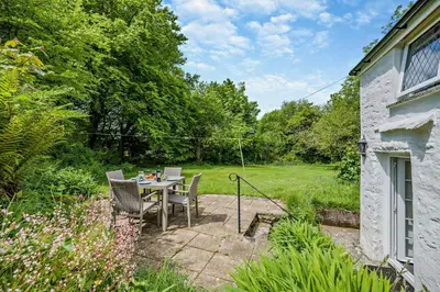 a patio with a table and chairs in a garden at 2 Bed in Advent oc-s6025 in Camelford