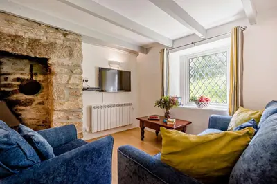 a living room with a blue couch and a stone fireplace at 2 Bed in Advent oc-s6025 in Camelford