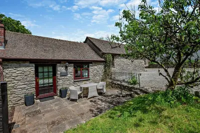 a stone house with a patio with a table and chairs at 1 Bed in Advent oc-b29387 in Camelford