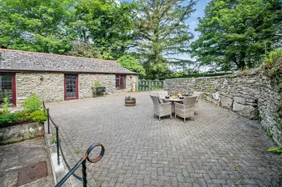 a patio with a table and chairs and a stone wall at 2 Bed in Advent oc-p6188 in Camelford