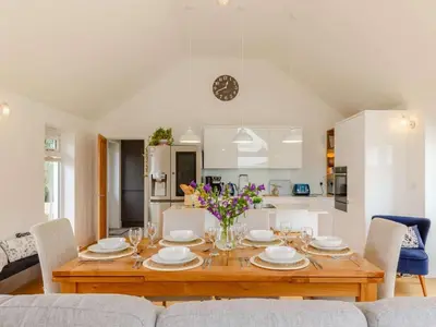 a dining room with a table and a kitchen at 3 Bed in Saltash oc-88525 in Landrake