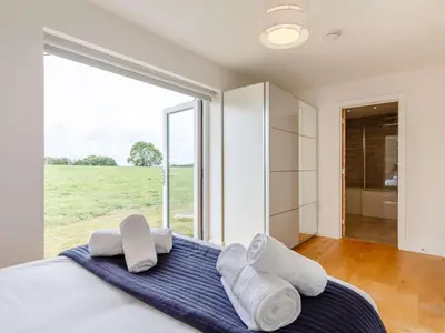 a bedroom with a bed with white pillows and a large window at 3 Bed in Saltash oc-88525 in Landrake