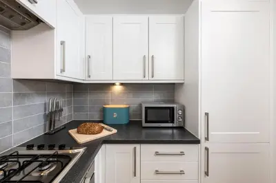 a kitchen with white cabinets and a microwave at 32 Tre Lowen in Newquay