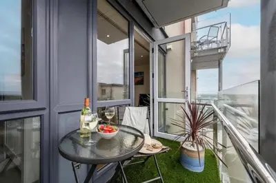 a balcony with a table and a bottle of wine at 32 Tre Lowen in Newquay