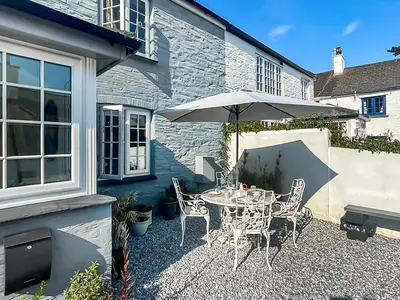 a patio with a table and an umbrella at Penty Lowen in Saint Mawes