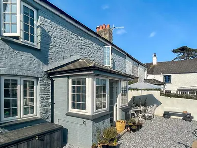 a stone house with a patio with a table and chairs at Penty Lowen in Saint Mawes