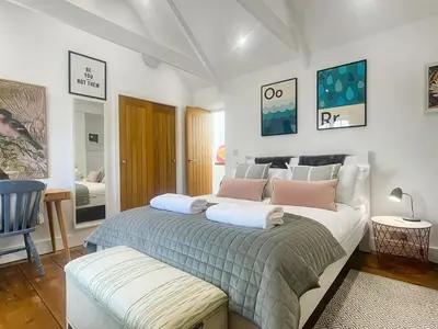 a bedroom with a large bed with pink pillows at Penty Lowen in Saint Mawes