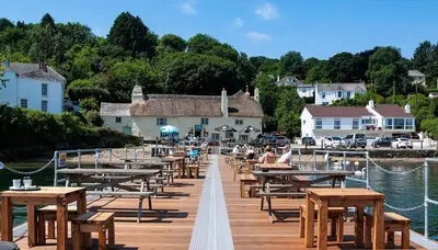 a wooden dock with tables and benches and a marina at Peaceful cottage with views - Fairview Cottage in Mylor Bridge