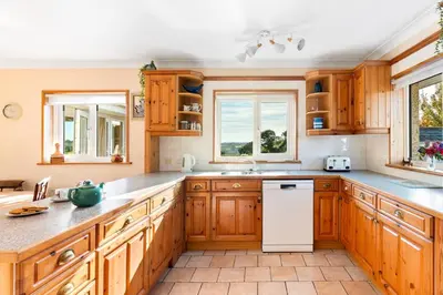 a kitchen with wooden cabinets and a white refrigerator at Peaceful cottage with views - Fairview Cottage in Mylor Bridge