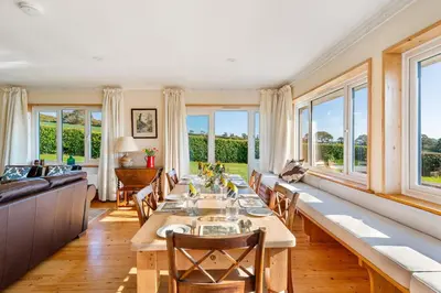 a dining room with a long table and windows at Peaceful cottage with views - Fairview Cottage in Mylor Bridge