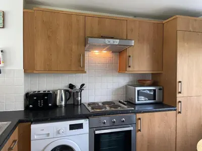 a kitchen with a stove and a microwave at Atlantic Reach – Cozy 2-Bed with Parking in Newquay