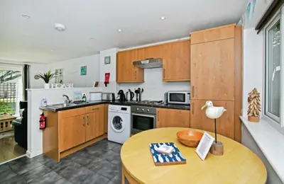 a kitchen with wooden cabinets and a wooden table at Atlantic Reach – Cozy 2-Bed with Parking in Newquay