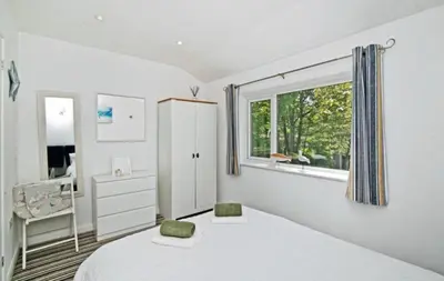 a white bedroom with a bed and a window at Atlantic Reach – Cozy 2-Bed with Parking in Newquay