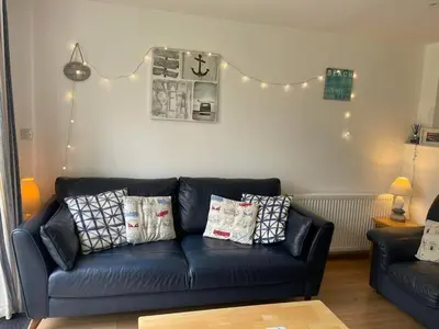 a living room with a black leather couch with pillows at Atlantic Reach – Cozy 2-Bed with Parking in Newquay