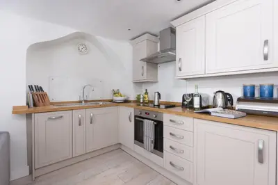 a kitchen with white cabinets and a sink at 4 Quayside - Centre of Fowey - Pet Allowed - Free WiFi in Fowey