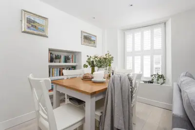 a dining room with a wooden table and white chairs at 4 Quayside - Centre of Fowey - Pet Allowed - Free WiFi in Fowey