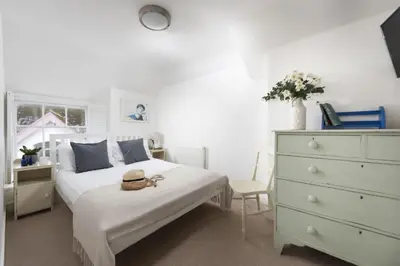 a bedroom with a bed with a dresser and a hat on it at 4 Quayside - Centre of Fowey - Pet Allowed - Free WiFi in Fowey