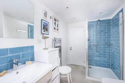 a bathroom with a sink and a shower with blue tiles at 4 Quayside - Centre of Fowey - Pet Allowed - Free WiFi in Fowey