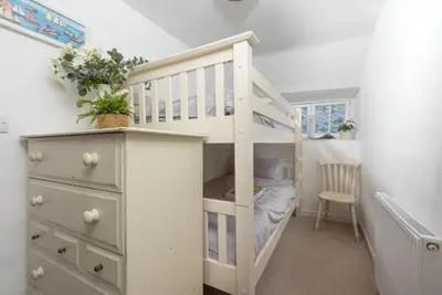 a white bunk bed in a small room with a dresser at 4 Quayside - Centre of Fowey - Pet Allowed - Free WiFi in Fowey