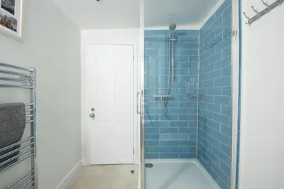 a blue tiled bathroom with a tub and a shower at 4 Quayside - Centre of Fowey - Pet Allowed - Free WiFi in Fowey