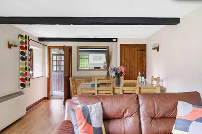 a living room and dining room with a brown leather couch at Myrtle Grove in Saint Endellion